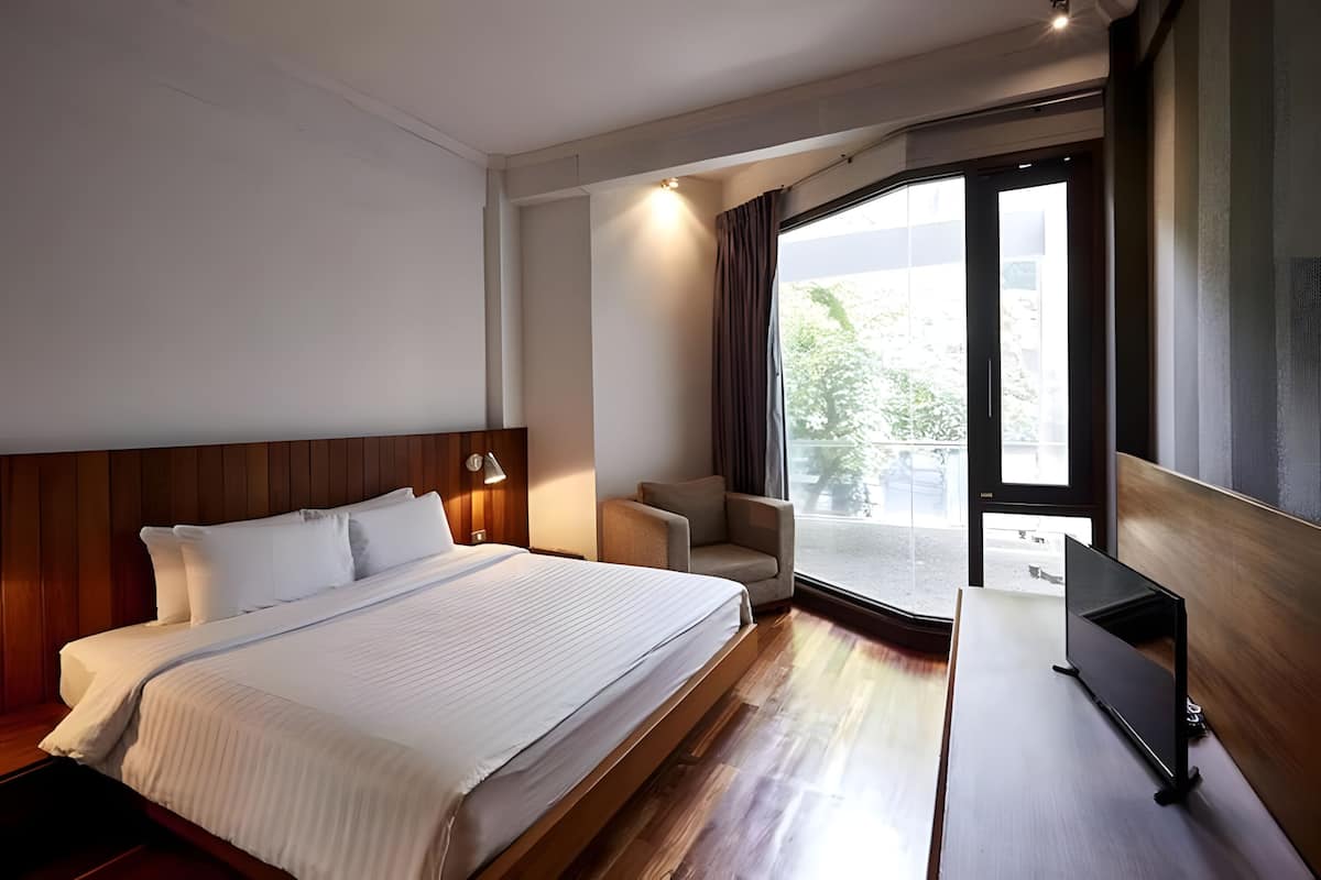Une chambre d’hôtel avec un lit, une télévision, une chaise et une grande fenêtre.