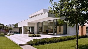 A modern house with a flat roof, large glass windows, and a paved patio. - Exclusive family villa with pool, jacuzzi and 3 luxury suites in Brabant (Goirle)