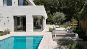A modern house with a swimming pool, outdoor seating, and a garden. - Exclusive family villa with pool, jacuzzi and 3 luxury suites in Brabant (Goirle)