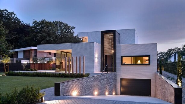 A modern house with a flat roof, a garage, and a paved driveway. - Exclusive family villa with pool, jacuzzi and 3 luxury suites in Brabant (Goirle)