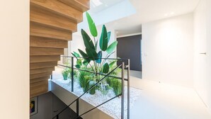 A modern staircase with a glass railing, a wooden ceiling, and a small indoor garden. - Exclusive family villa with pool, jacuzzi and 3 luxury suites in Brabant (Goirle)