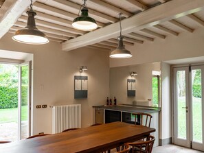 A modern kitchen with a central island, pendant lighting, and a view of greenery outside. - L'Orto di Vignamaggio (Greve in Chianti)