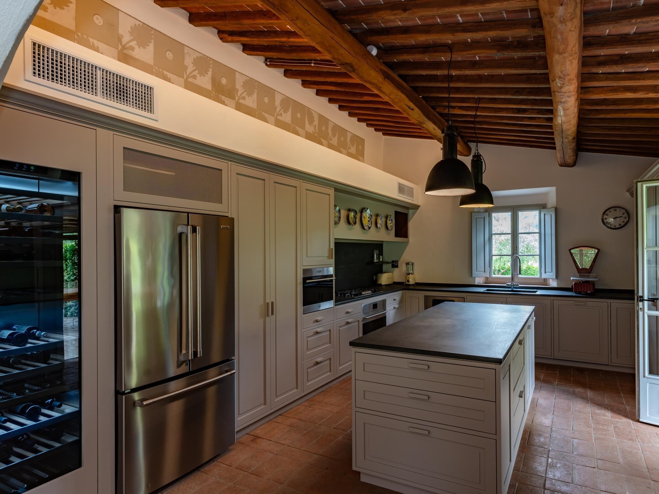 A kitchen with stainless steel appliances, white cabinetry, and a large island.