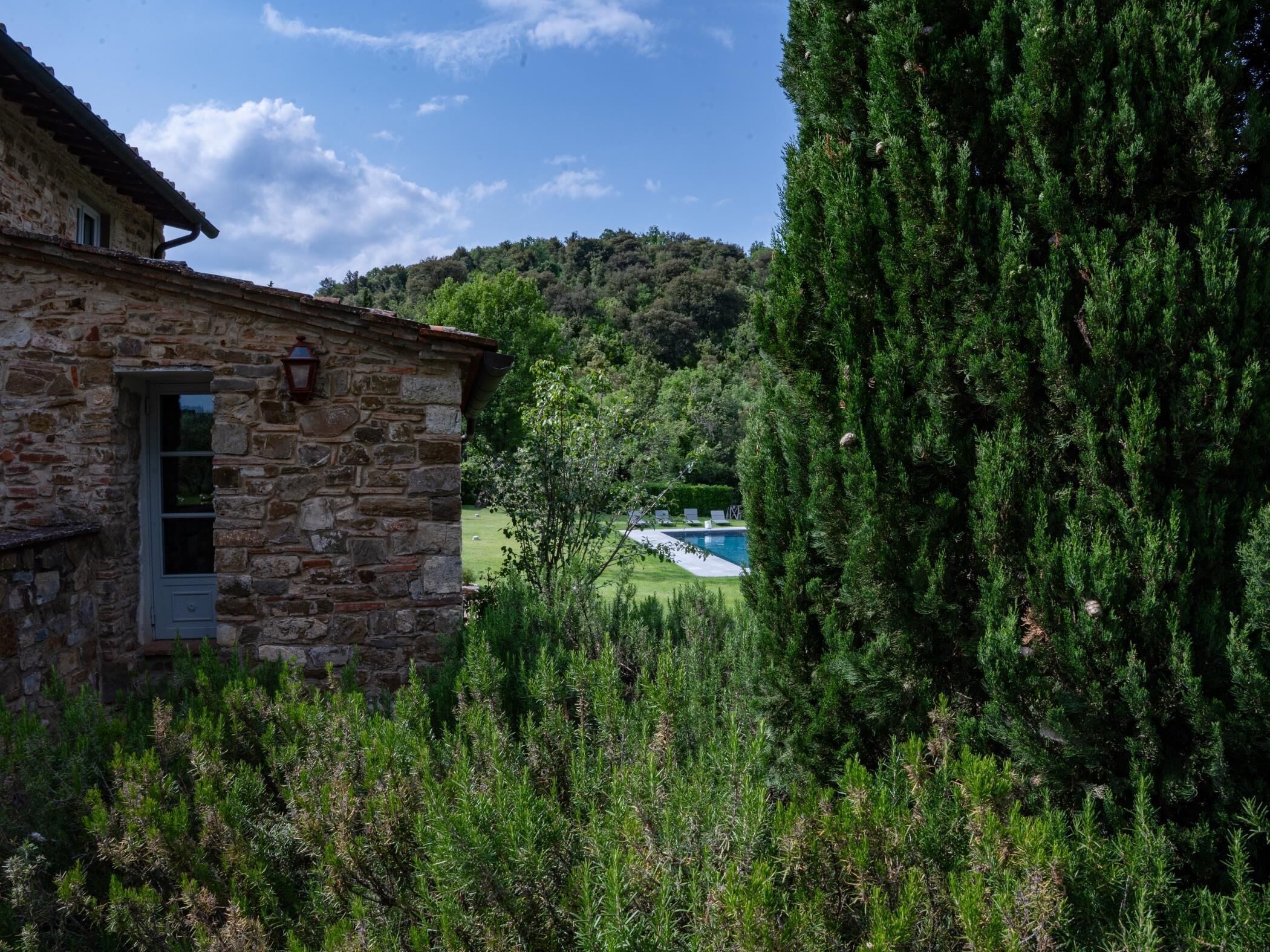 Ein Steinhaus mit Pool und Blick auf einen bewaldeten Hügel.