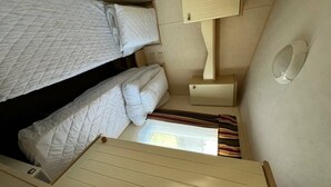 A compact room with bunk beds, a small bedside table, a lamp, and a window. - Primrose Valley Holiday Park - Holiday Accommodation 1421 (Filey)