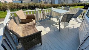A covered outdoor patio with wicker furniture, a table, and chairs. - Primrose Valley Holiday Park - Holiday Accommodation 1421 (Filey)