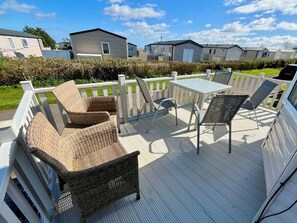 Eine überdachte Terrasse im Freien mit Korbmöbeln, einem Tisch und Stühlen.