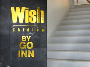 Uma escadaria com uma placa que diz 'Wish Chidlom BY GO INN'.