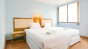 Ein Hotelzimmer mit einem großen Bett, Nachttischlampen, einem Nachttisch und einem Fenster.