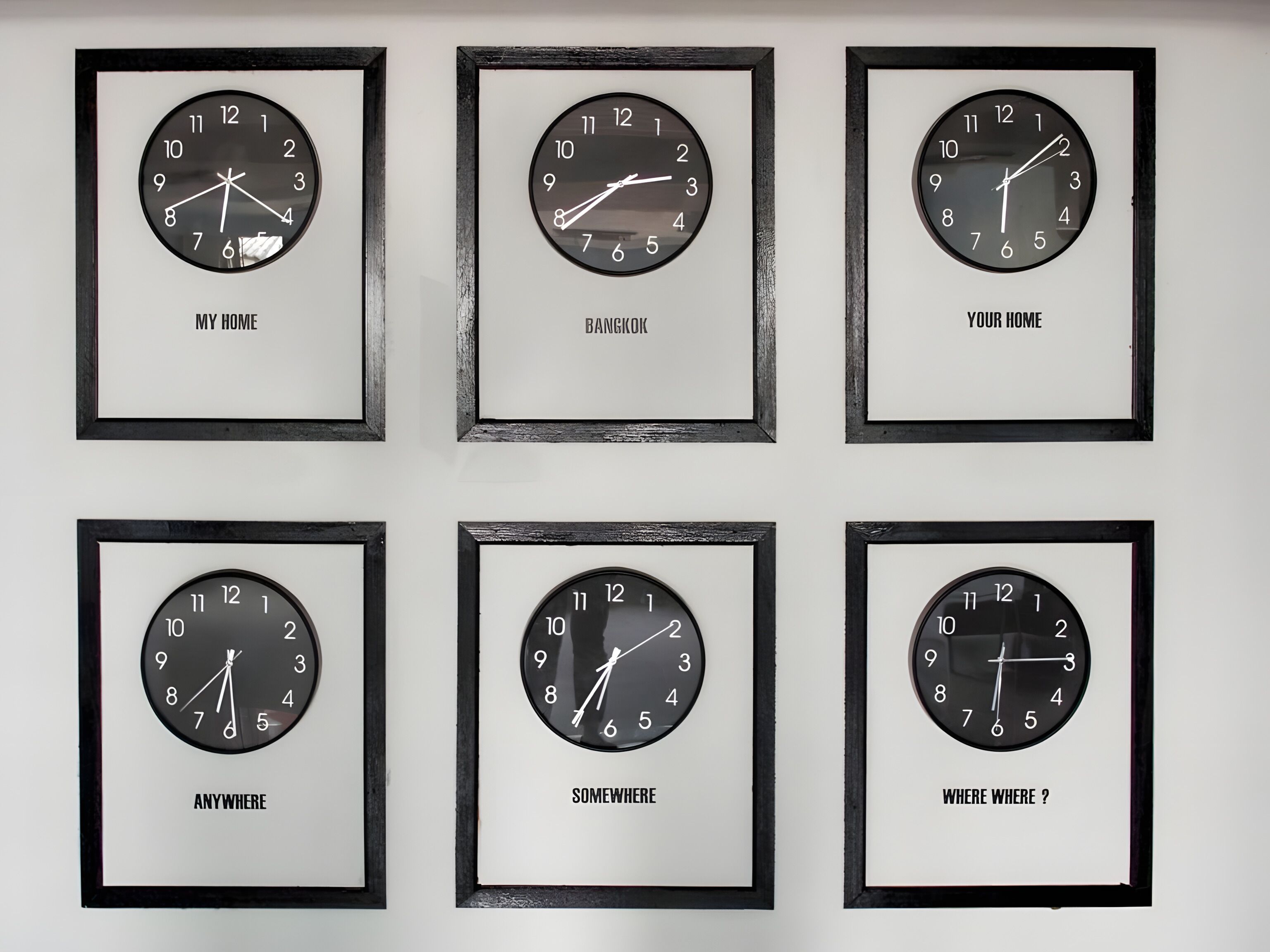 Six framed wall clocks with different phrases below them.