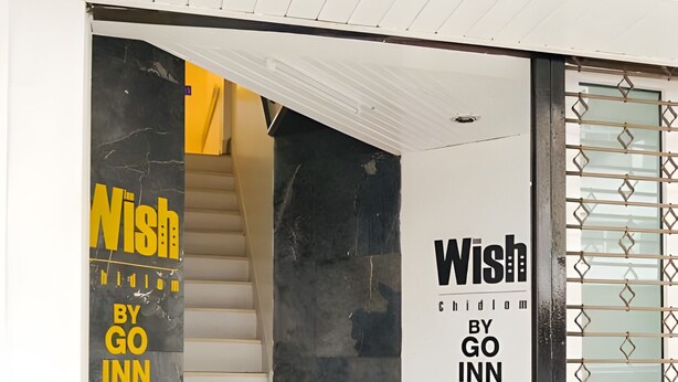 Eine Treppe führt zu einem Raum, der in Schwarz-Weiß gehalten ist und ein Schild mit der Aufschrift 'Wish by Go Inn'.
