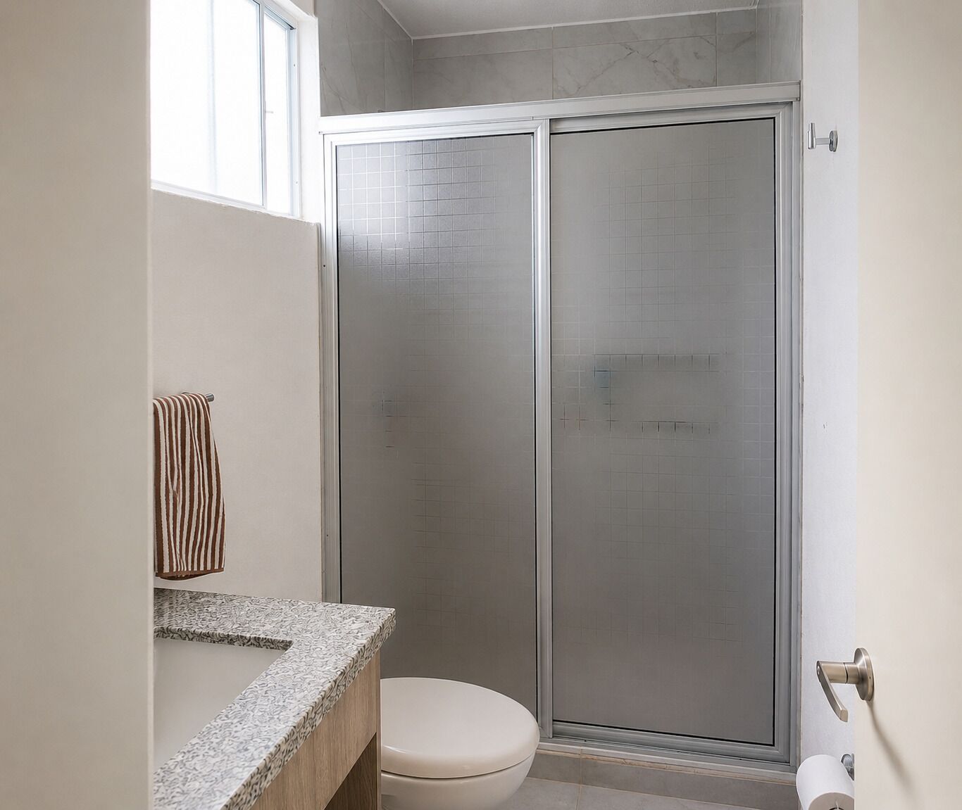 Une salle de bain avec une douche, des toilettes et un porte-serviettes.