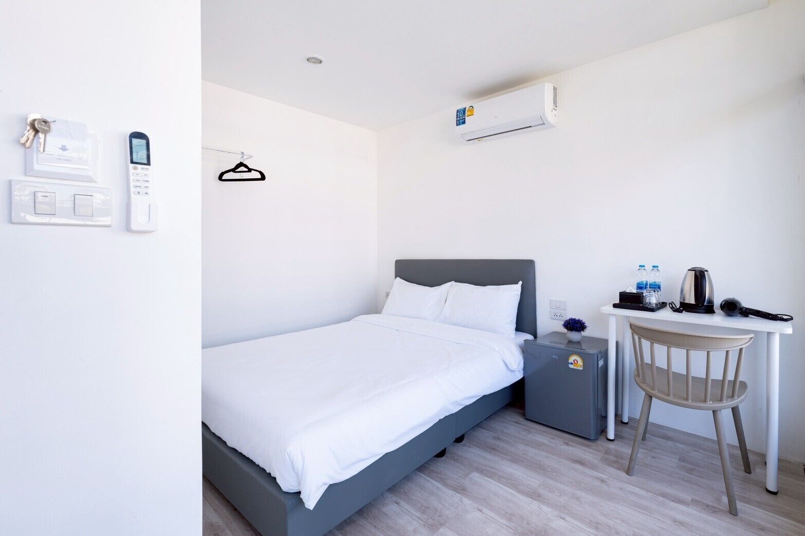Een hotelkamer met een bed, nachtkastje, bureau, stoel en een airconditioning.