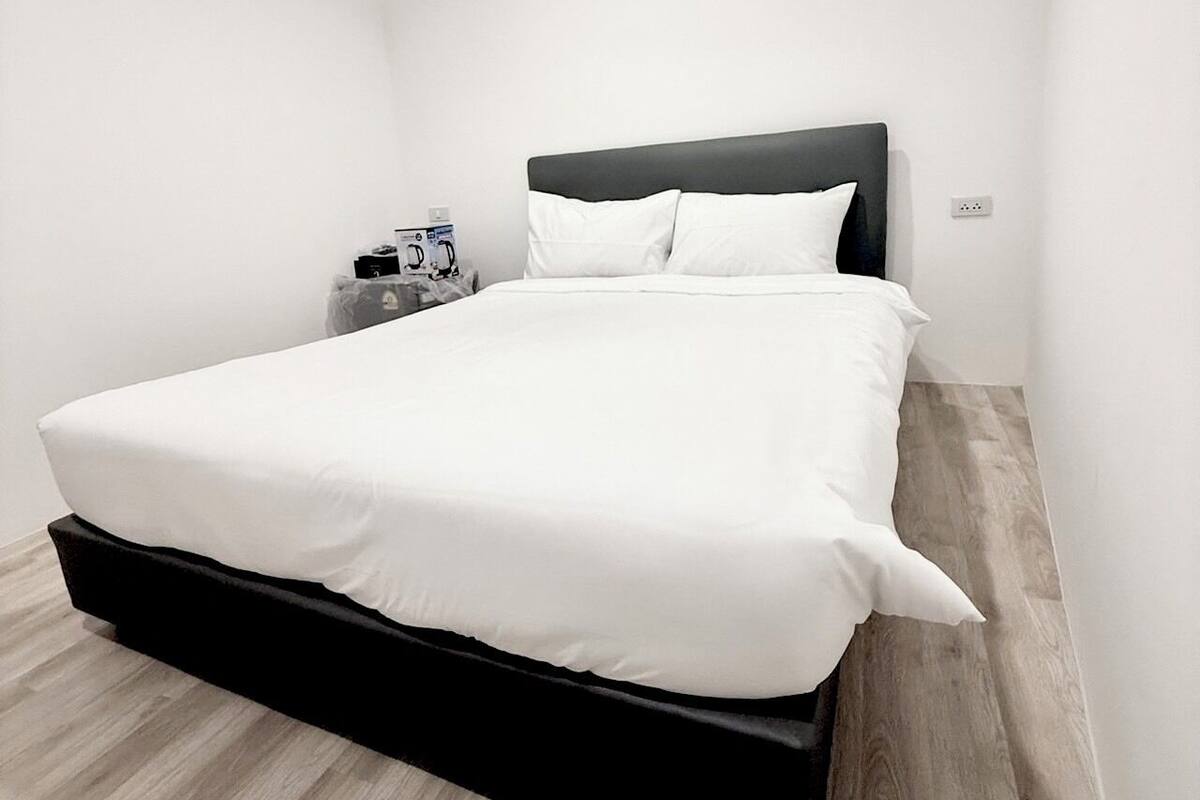 Una habitación de hotel moderna con una cama grande, una mesita de noche y una cafetera.