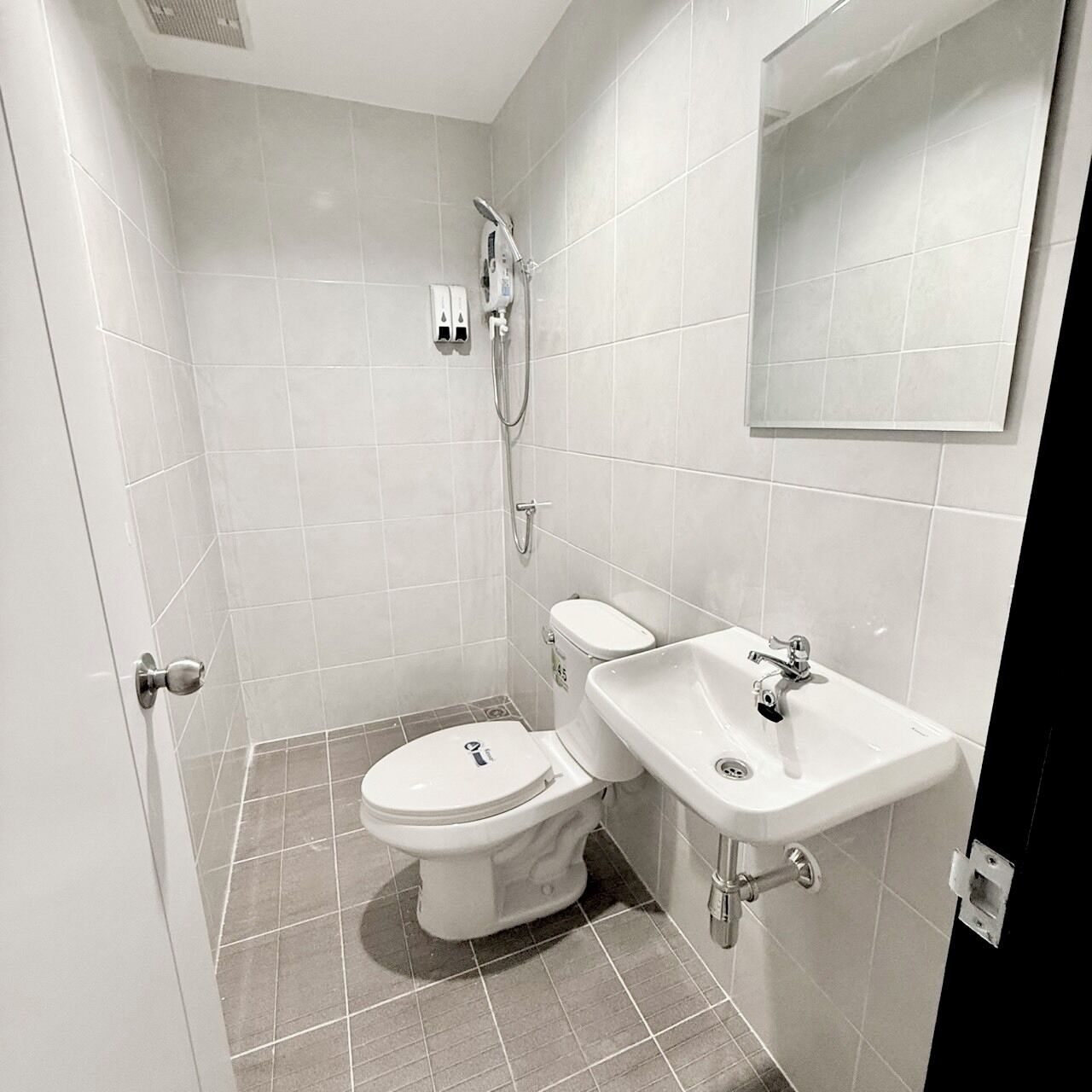 Un baño pequeño y moderno con inodoro, lavamanos y ducha.