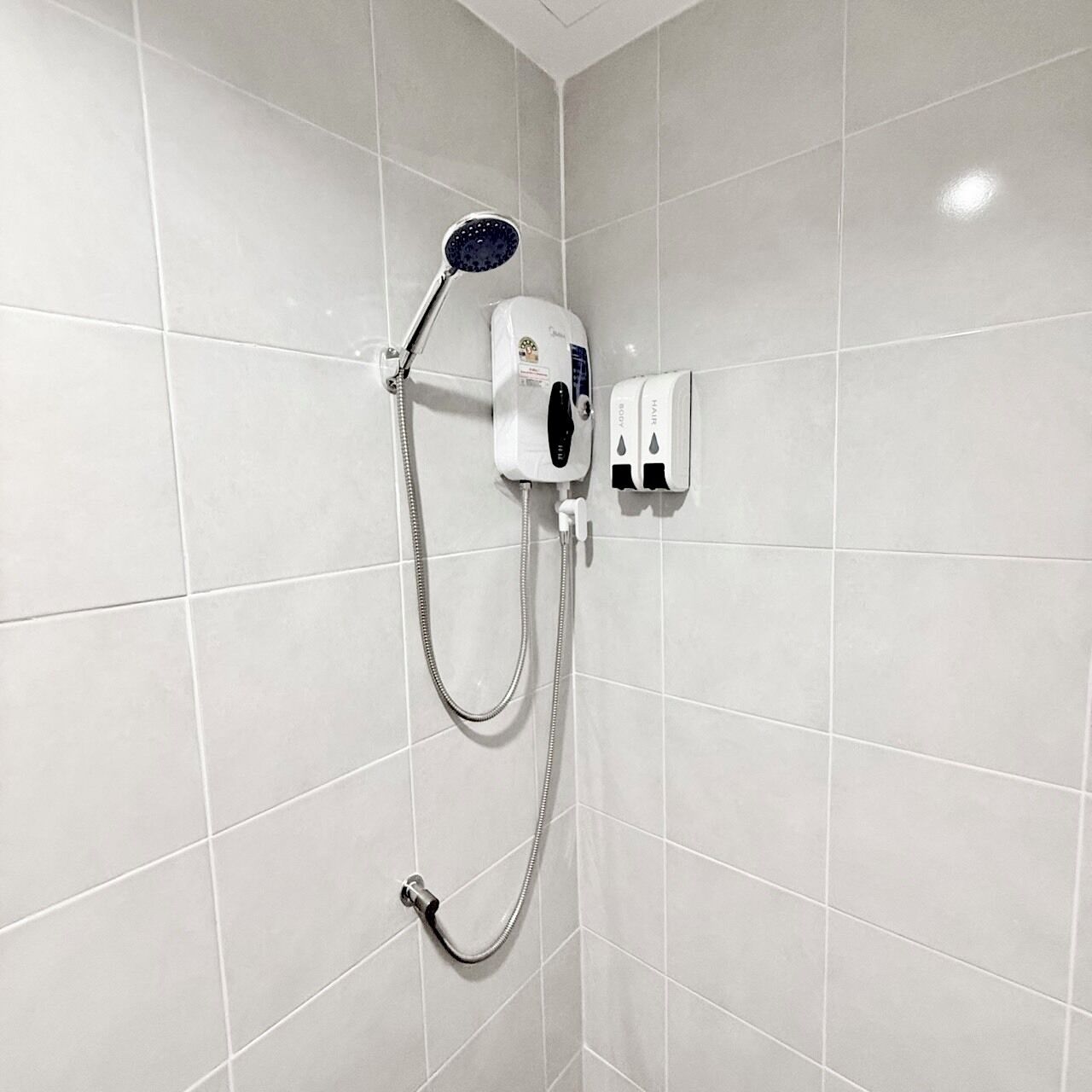 A shower with a handheld showerhead and a wall-mounted control panel.