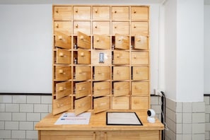 Een houten opbergkast met verschillende vakken, een beveiligingscamera en een bord met afchecktijden.