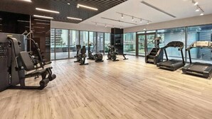 A gym with various exercise equipment, large windows, and a modern design. - Mesmerizing 2 Bed l Canal and Burj Views (Al Wasl)
