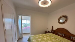 A bedroom with a bed, a nightstand, a mirror, and a door leading to a balcony. - Beautiful mountain apartment with sea views AV 91 (ROSES)