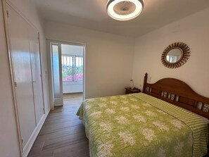 Ein Schlafzimmer mit einem Bett, einem Nachttisch, einem Spiegel und einer Tür, die auf einen Balkon führt.