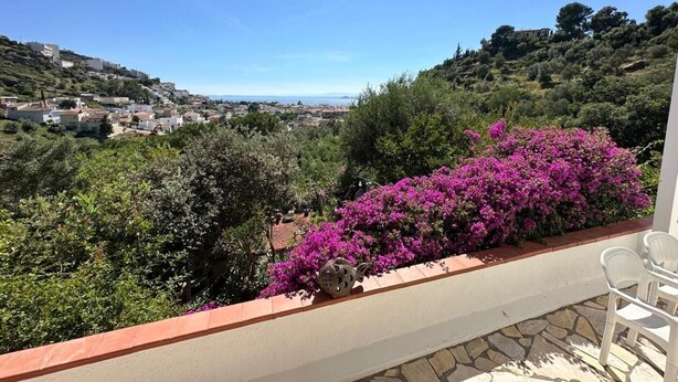 A balcony with a view of a hillside town, a stone floor, and a red awning. - Beautiful mountain apartment with sea views AV 91 (ROSES)
