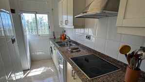 A kitchen with a built-in stove, a sink, and a window. - Beautiful mountain apartment with sea views AV 91 (ROSES)