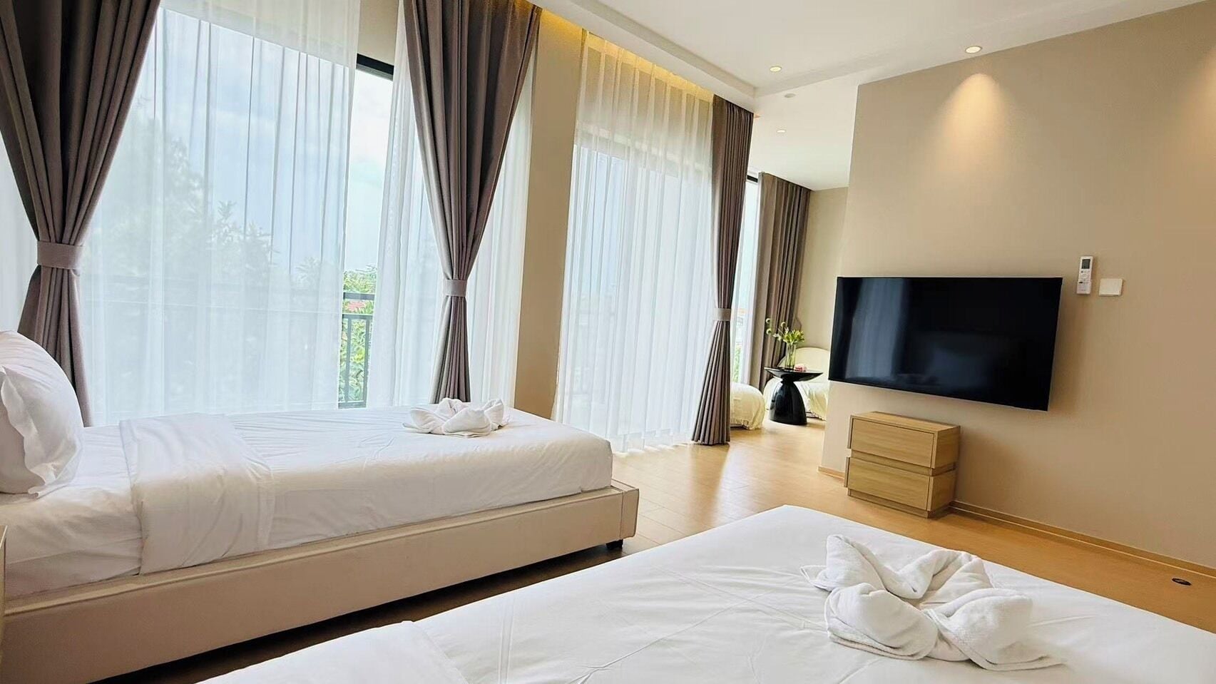 Ein Hotelzimmer mit zwei Betten, einem Flachbildfernseher und einem großen Fenster mit Vorhängen.