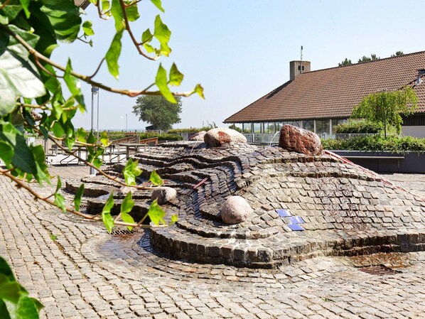 Un sitio arqueológico al aire libre con estructuras de piedra y un edificio moderno al fondo.