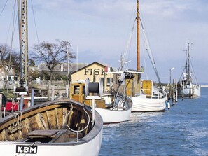 Ein Hafen mit mehreren vertäuten Booten, ein hölzernes Gebäude mit der Aufschrift 'FISH' und einem Schild 'KBM'.
