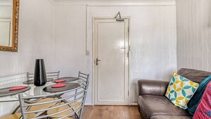 Una stanza con un tavolo da pranzo, sedie, un divano, una porta e uno specchio.