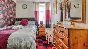 Una camera da letto con un letto, una cassettiera, uno specchio e delle tende.