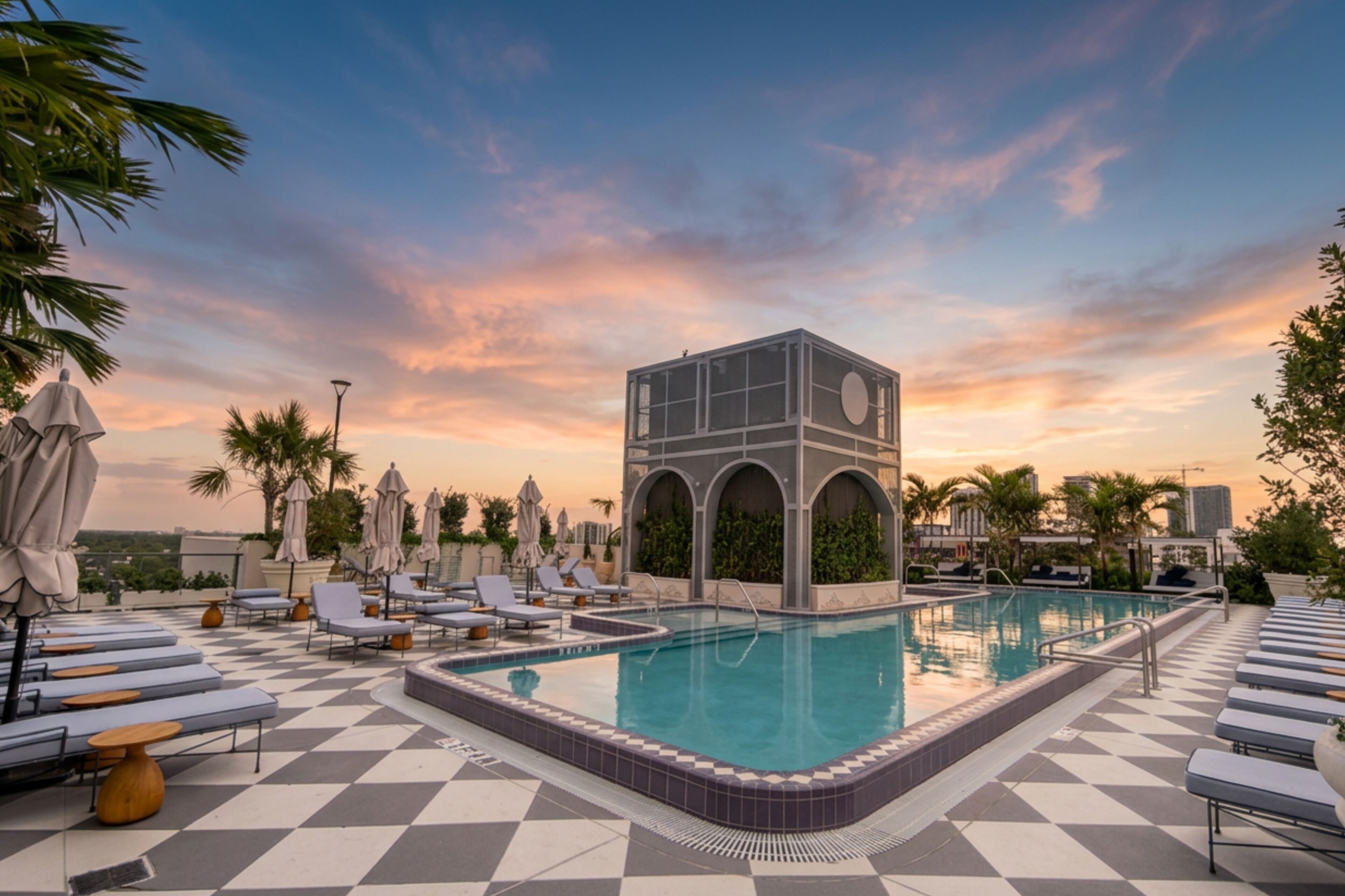 Área de piscina en la azotea con sillones de descanso, una piscina y un edificio con arcos.