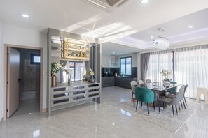 Ein modernes Interieur mit Essbereich, Küche und einem großen Fenster mit Vorhängen.