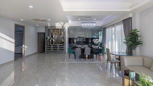 A modern living room with a dining area, a kitchen in the background, and a staircase leading to another level. - Spacious 5-bedroom house in charming Muang Pattaya C25 (Muang Pattaya)