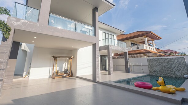 A modern two-story house with a swimming pool, a sun lounger, and a yellow inflatable toy. - Spacious 5-bedroom house in charming Muang Pattaya C25 (Muang Pattaya)