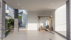 A spacious room with a minimalist design, featuring a large window, a swing chair, and a view of the outside. - Spacious 5-bedroom house in charming Muang Pattaya C25 (Muang Pattaya)
