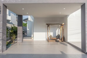 Ein geräumiger Raum im minimalistischen Stil mit einem großen Fenster, einem Schaukelstuhl und Blick ins Freie.