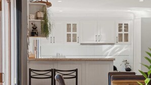 A compact kitchen with white cabinets, a dining table, and chairs.