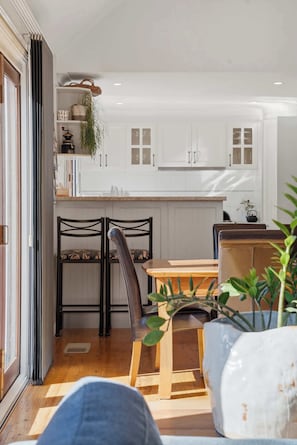 Une cuisine de taille réduite avec des meubles blancs, une table à manger et des chaises.