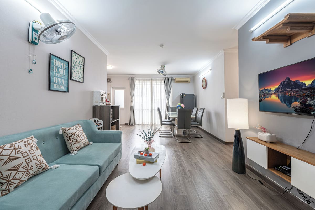 A modern living room with a sofa, coffee table, dining area, and TV.