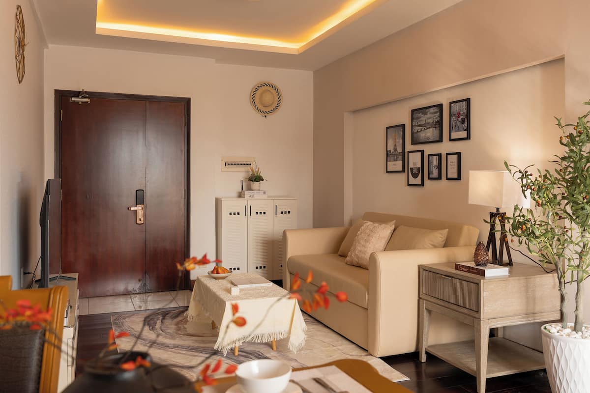 A living room with a sofa, a coffee table, a TV, a door, and a wall with framed pictures.