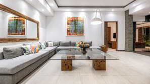A modern living room with a glass coffee table, grey sofa, and abstract paintings. - Elegant 3BR Oasis in the Heart of Seminyak (Seminyak)