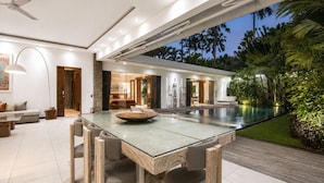 Un intérieur moderne avec une table à manger en verre, une piscine et une vue sur l’extérieur.