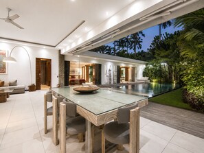 A modern interior with a glass dining table, a pool, and a view of the outdoors. - Luxury 3-bedroom Villa With Pool Central Seminyak (Seminyak)