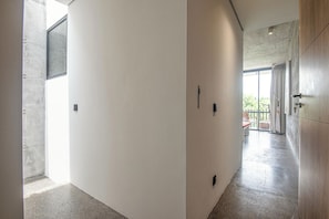 A modern hallway with a concrete wall, a wooden door, and a glass door leading to a balcony. - Modern 2BR Villa Enclosed Living, Heart of Canggu (Kerobokan)