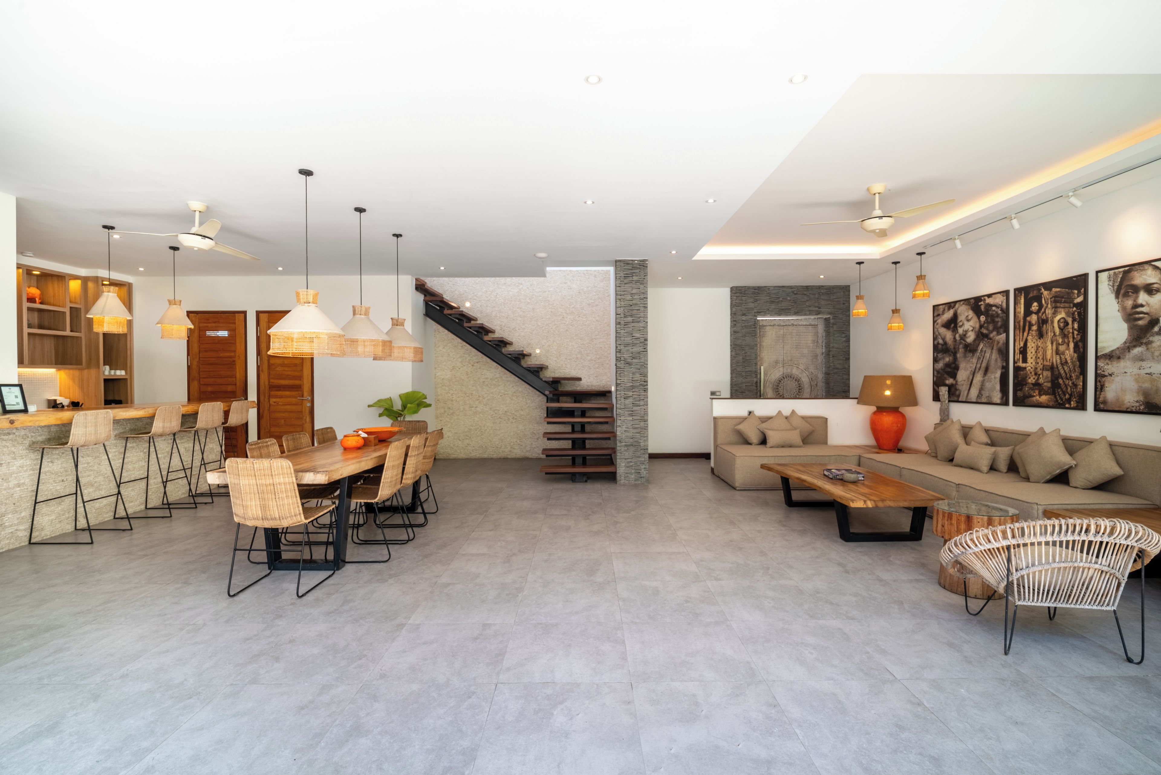 A spacious living area with a dining table, sofas, and a staircase.