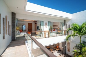 Ein modernes Interieur mit einem Glasbalkon, einer Sitzecke mit Kissen und einem Holzboden.