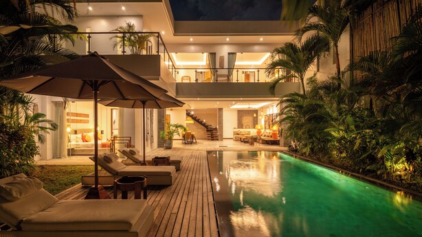 A modern poolside area with lounge chairs, a wooden deck, and a staircase leading to an upper level. - Canggu Coastal Living: 4BR Villa Near Finns (Canggu)
