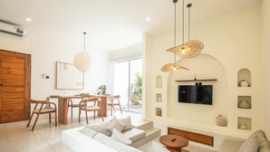 Ein modernes Wohnzimmer mit einer Couch, einem Essbereich und einem Fernseher.