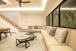 Un salon moderne avec un canapé, une table basse et un escalier.